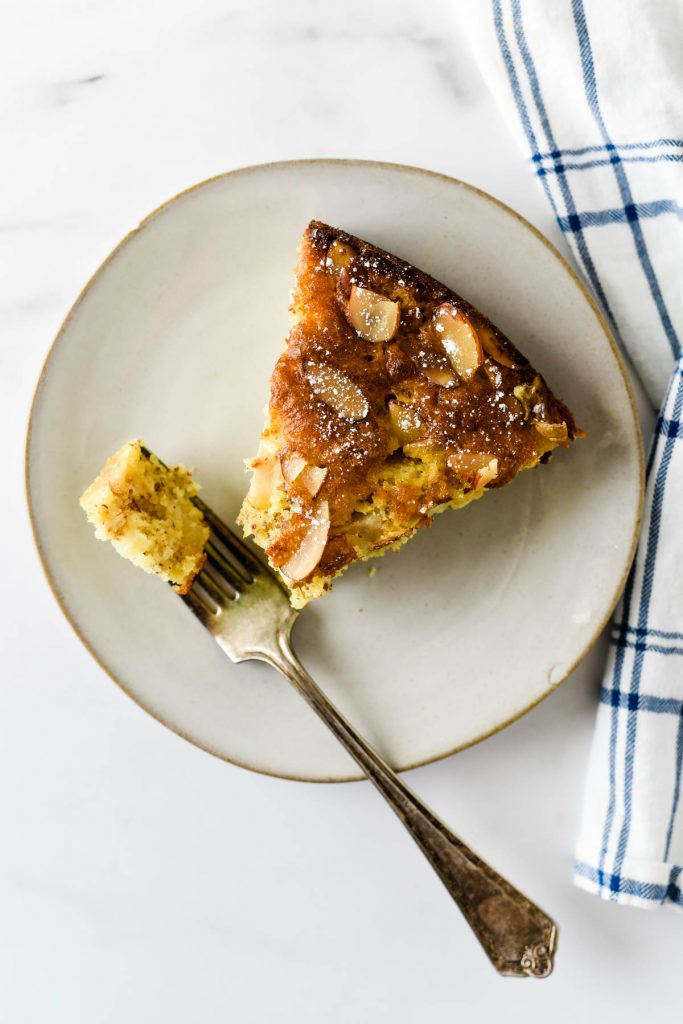 small plate with piece of pear almond cake and fork with bite on it