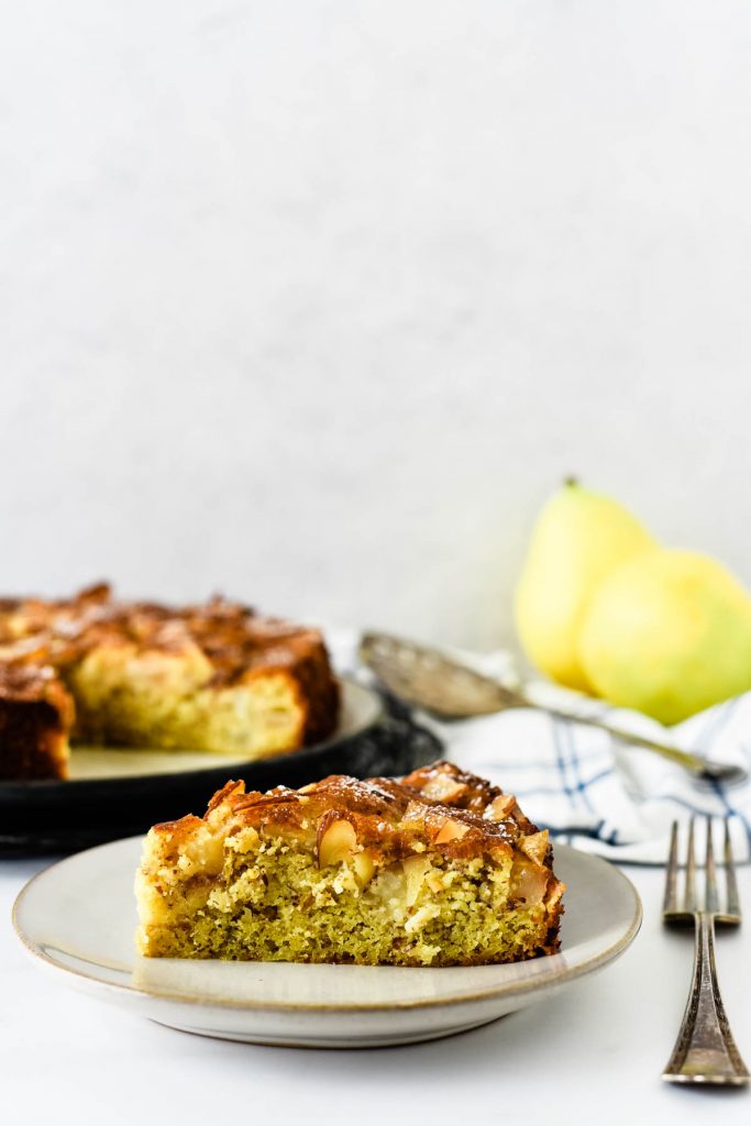 pear cake on place with serving platter and pears behind