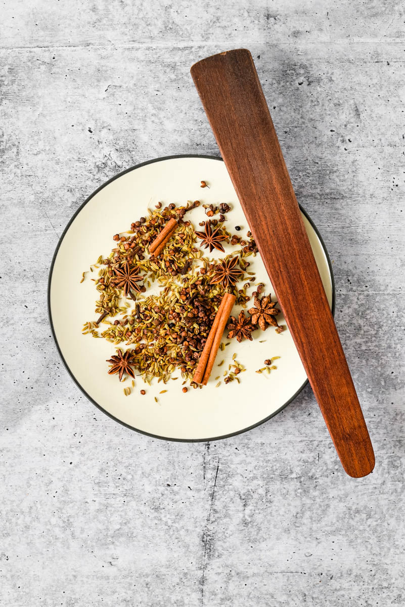 spices for chinese five spice blend on plate with wooden spatula