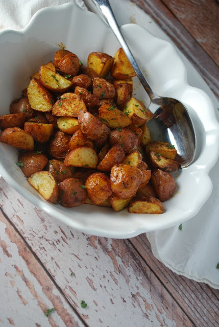 Dijon Roasted Potatoes - The Gingered Whisk white bowl with roasted dijon potatoes and serving spoon