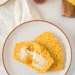 two slices of mealie bread on white plate smeared with butter and drizzled with honey