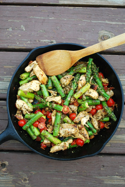One Pan Pesto Chicken and Veggies - healthy, quick, family friendly weeknight meal A cast iron skillet filled with skillet pesto chicken and veggies with a wooden spoon