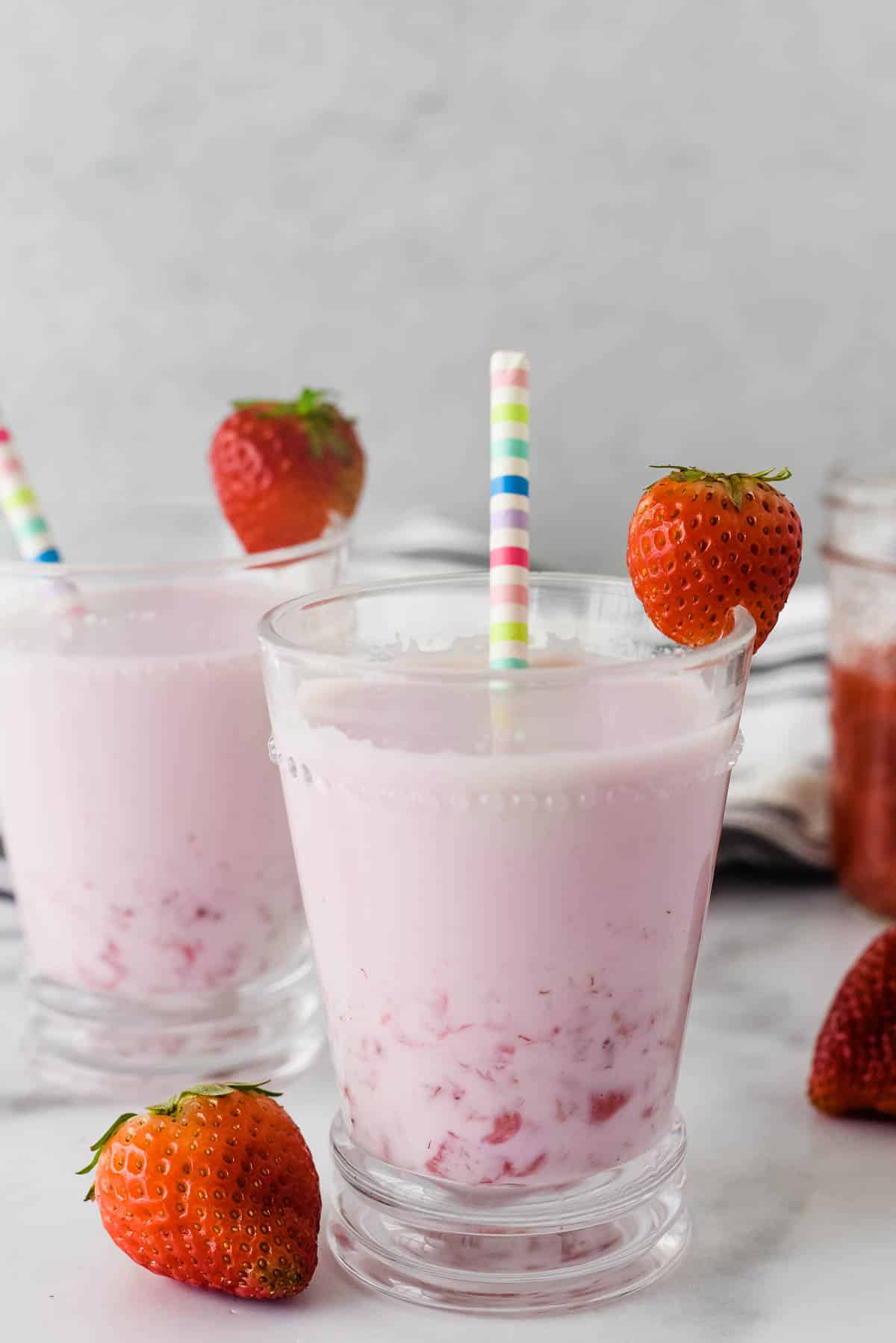 strawberry milk in a glass with strawberries and striped straw