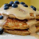 stack of three sweet potato pancakes with homemade syrup drizzle and fresh blueberries
